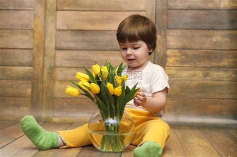 一个拿着一束黄色郁金香的小孩一个男孩拿着花瓶里的鲜花礼物给女假期女孩的礼物高清图片下载-正版图片506246734-摄图网