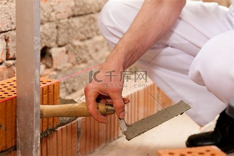 砌砖工人正在砌砖做一堵墙，他正在检查他的工作腿五金高清摄影大图-千库网