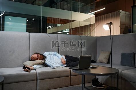 过度劳累的僵尸员工睡在办公室的沙发上。高清摄影大图-千库网