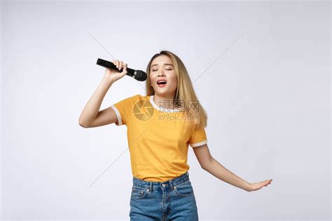 美丽的亚洲女人唱着歌给麦克风白色背景高清图片下载-正版图片505758052-摄图网