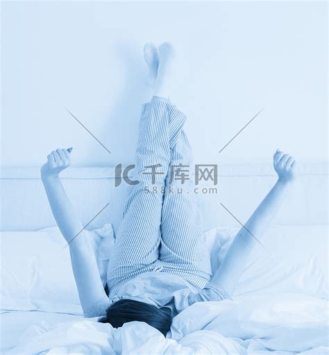 躺在床上的年轻女人，双腿高高地靠在墙上高清摄影大图-千库网