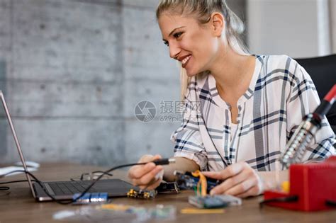 年轻女技术员的重点是通过焊接铁修理电子设备高清图片下载-正版图片504478412-摄图网