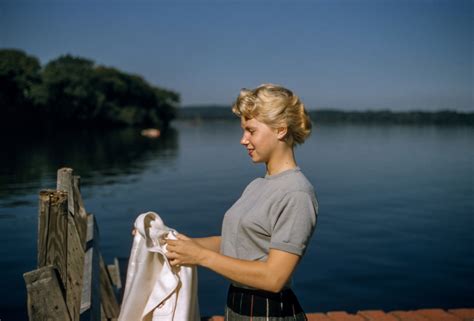 woman with a vintage updo hairstyle holding a jacket by the lake ...