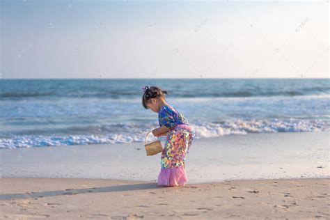 捡贝壳的小姑娘背影下午女孩背影海边捡摄影图配图高清摄影大图-千库网