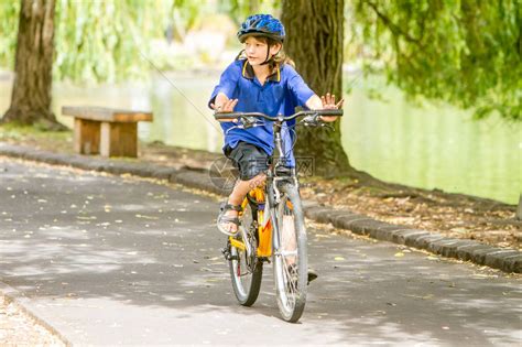 在自然公园背景下骑自行车的快乐青春期前男孩高清图片下载-正版图片507368547-摄图网