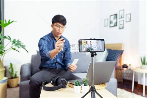 年轻的亚洲男博主在家办公室对产品的相机评论录制vlog视频高清图片下载-正版图片506634774-摄图网