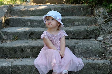 一个小女孩坐在古老的石阶上，神情恍惚