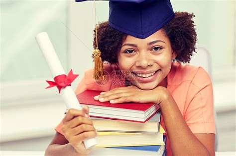 教育,学校,毕业人的快乐的微笑非裔美国学生女孩戴着学士帽,书文凭坐家里的桌子上高清图片下载-正版图片300605537-摄图网