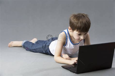 男孩带着电脑躺在地上拿高清图片下载-正版图片504484327-摄图网