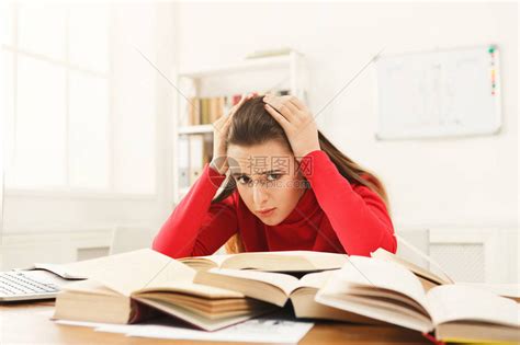 疲倦的女孩在工作台上学习精疲力竭的女学生看书和在笔记本电脑上工作教高清图片下载-正版图片502814745-摄图网