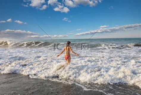 一个年轻女子在海边的海浪中玩耍高清摄影大图-千库网