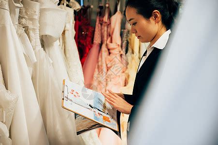婚纱店内整理婚纱的婚礼策划师形象高清图片下载-正版图片502044507-摄图网