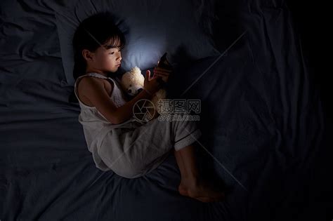 小女孩夜晚躺床上玩手机高清图片下载-正版图片501556314-摄图网
