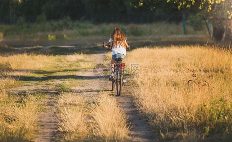 妇女骑自行车在草地上的泥土路高清图片下载-正版图片304281949-摄图网