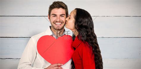 男人拿着纸心被女友亲吻的合成图高清摄影大图-千库网