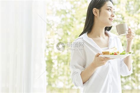 手拿茶杯和食物的年轻女孩高清图片下载-正版图片502276316-摄图网