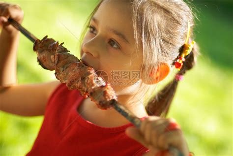 快乐的小女孩吃烤羊肉串高清图片下载-正版图片503595125-摄图网