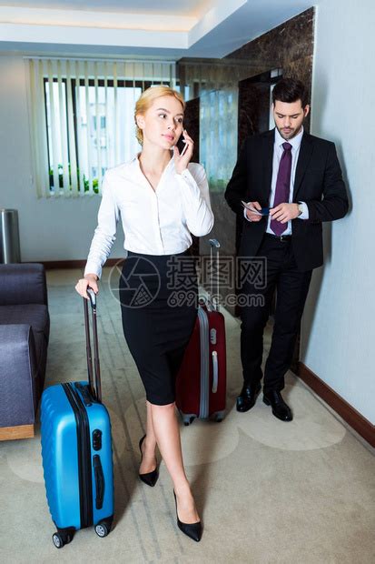 在旅馆走廊用智能手机说话的漂亮商高清图片下载-正版图片505100144-摄图网