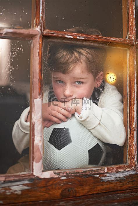 又下雨了……一个小男孩坐在窗边，外面正在下雨，看起来很无聊。高清摄影大图-千库网