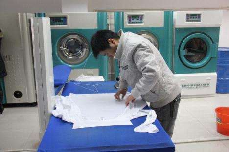 干洗店工人在衣服上贴标签高清图片下载-正版图片503748245-摄图网