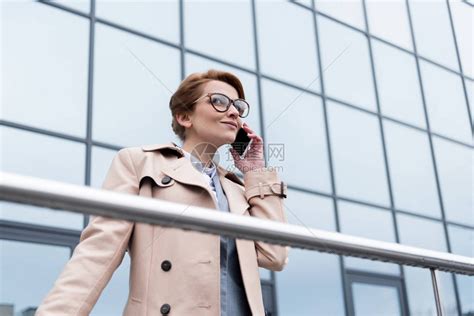 笑的女商人在街上用智能手机聊天高清图片下载-正版图片503360225-摄图网
