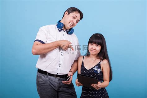 亚洲女友拿着平板电脑，白人男友在工作室里指着它高清摄影大图-千库网